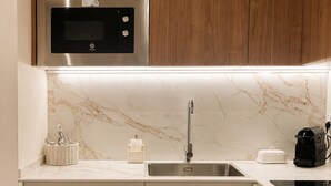 Una cocina moderna con armarios de madera, un microondas de acero inoxidable, un salpicadero de mármol, un fregadero y un horno empotrado.