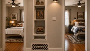 Ein Flur mit einer zentralen Regaleinrichtung, zwei Schlafzimmer mit Holzböden und Deckenventilatoren.