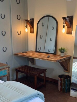 Ein Zimmer mit einem Holztisch, einer Bank, einem Spiegel mit Hufeisen-Motiven und Wandleuchten.