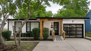 Ein modernes, zweistöckiges Haus mit Veranda, Garage und gepflegtem Rasen.