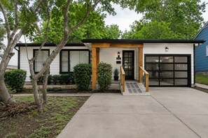 Ein modernes, zweistöckiges Haus mit Veranda, Garage und gepflegtem Rasen.