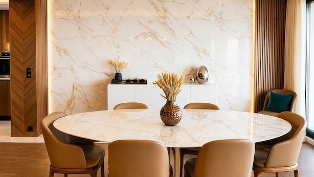 Un comedor moderno con una mesa de mármol, sillas de cuero y un aparador de madera con objetos decorativos.