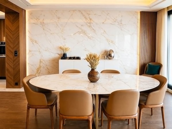 Un comedor moderno con una mesa de mármol, sillas de cuero y un aparador de madera con objetos decorativos.