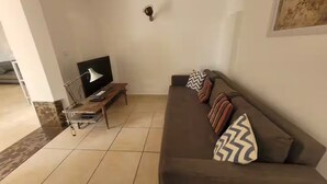 A living room with a sofa, a coffee table, a TV, and a lamp. - Family Home - Peaceful, with a Pool and Surrounded by Nature, 4 km from the Sea (Fréjus)