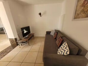 Ein Wohnzimmer mit Sofa, Couchtisch, Fernseher und Lampe.