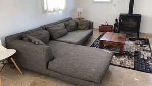 A living room with a sofa, a coffee table, a fireplace, and a window. - Family Home - Peaceful, with a Pool and Surrounded by Nature, 4 km from the Sea (Fréjus)