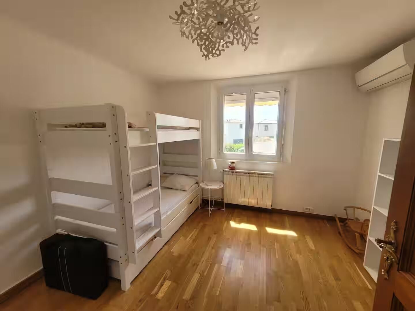A room with a bunk bed, a radiator, a window, and a door.