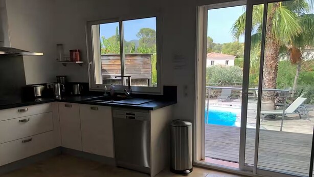 A modern kitchen with a built-in dishwasher, a large window, and a view of a pool. - Family Home - Peaceful, with a Pool and Surrounded by Nature, 4 km from the Sea (Fréjus)
