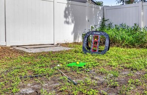 Un jardin avec un trampoline, un tapis vert et un ballon jaune.