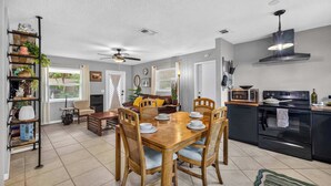 A modern kitchen with a dining area, featuring a wooden table, chairs, and a built-in oven. - The Landing Pad | Pet Friendly Yard (Tampa)