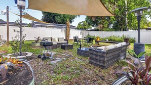 An outdoor patio area with wicker furniture, a barbecue grill, and a table with chairs. - The Landing Pad | Pet Friendly Yard (Tampa)