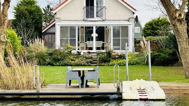 Ein Haus mit Balkon, einem Steg und einem kleinen Boot.