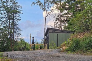 A gravel path leading to a building with a green exterior, surrounded by trees and vegetation.