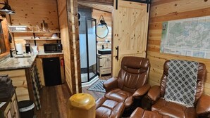 A cabin interior with a kitchen, seating area, and a map on the wall.