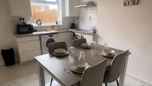 Una cocina moderna con una mesa de comedor para cuatro personas, lavadora y estufa.