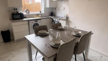 A modern kitchen with a dining table set for four, a washing machine, and a stove.