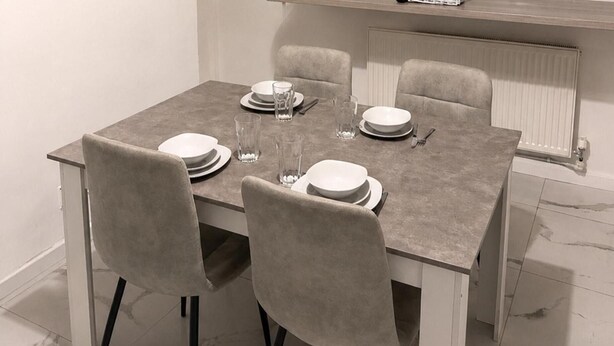 Una mesa de comedor servida con platos, vasos y cubiertos.
