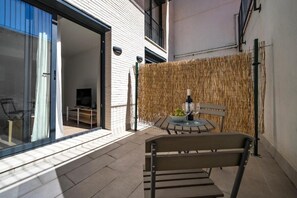 An outdoor patio with a table and chairs, a bottle of wine, and a basket of fruit. - Teatre Aparthotel Habitat Apartments (L'Hospitalet de Llobregat)