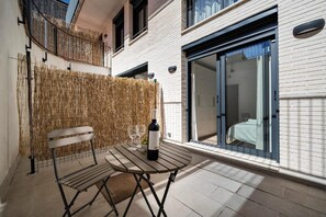 Een balkon met een tafel, een stoel en een fles wijn.