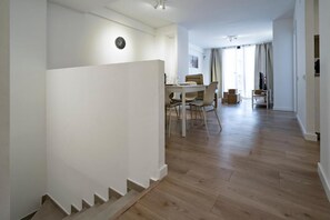A modern interior with a staircase, a dining area with a table and chairs, and a view of a room with a bed. - Teatre Aparthotel Habitat Apartments (L'Hospitalet de Llobregat)