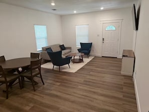 A living room with a sofa, two armchairs, a coffee table, and a dining table with chairs. - Newly Built Denison White House Stay - EV Ch (Denison)