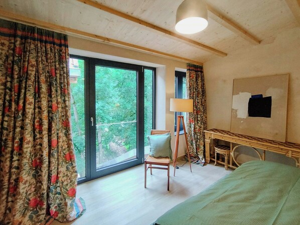 A room with a bed, a chair, a table, a lamp, and a window with curtains. - Hayloft apartment in the Rhön Biosphere Reserve (Gersfeld)