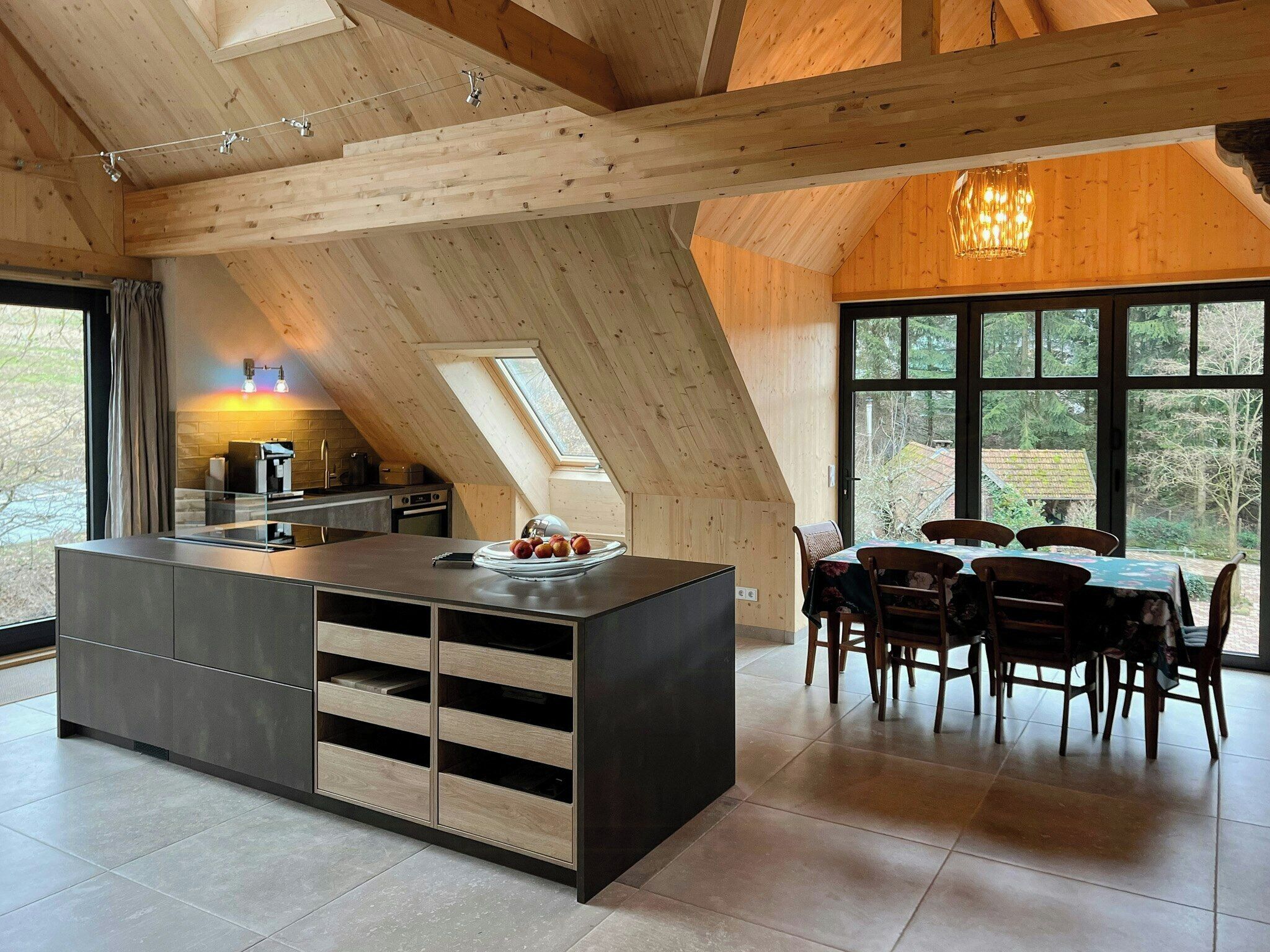 Eine moderne Küche mit Kochinsel, Holzbalken und einem Essbereich mit Tisch und Stühlen.