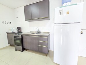 Eine kleine Küche mit Mikrowelle, Kaffeemaschine, Spüle und Kühlschrank.