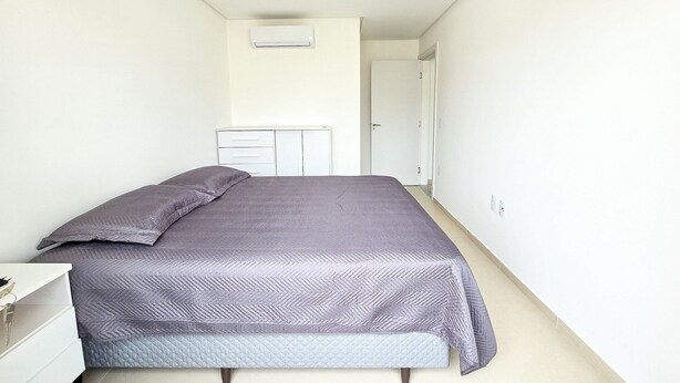 A bedroom with a bed, a bedside table, a wardrobe, and a door leading to another room. - La Rosadita by LikeHome  (Bombinhas)