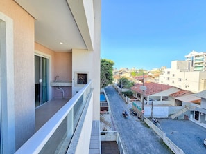 A balcony with a sink and a window, overlooking a street with parked motorcycles and buildings.