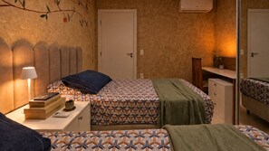 Ein Schlafzimmer mit zwei Betten, einem Nachttisch mit Lampe, einer Kommode und einem Spiegel.