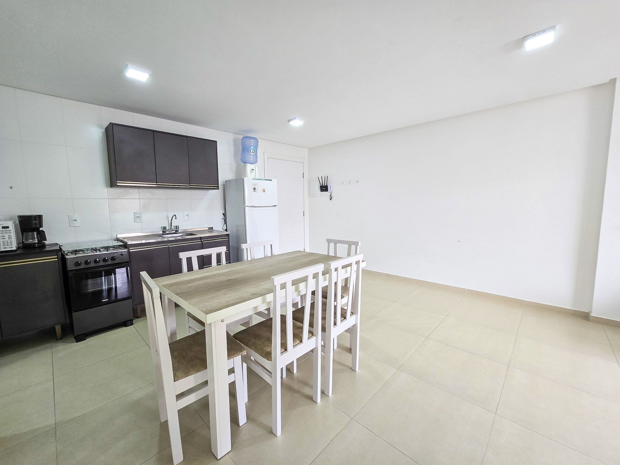 A compact kitchen with a dining table and chairs, a refrigerator, and a stove.