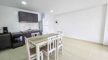 A compact kitchen with a dining table and chairs, a refrigerator, and a stove.