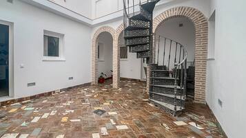 Een ruim interieur met een centrale trap, witte muren en een vloer met patroon.