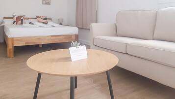 A hotel room with a bed, a round wooden table, and a white sofa.