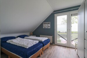 Une chambre avec deux lits, une fenêtre et une vue sur l’extérieur.