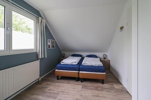 A bedroom with two beds, a window, and a radiator. - Waterfront Makkum Bungalow With Jetty (Makkum)