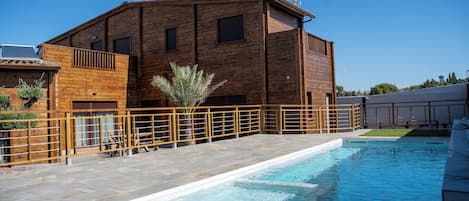 A modern building with a swimming pool, wooden deck, and a satellite dish.