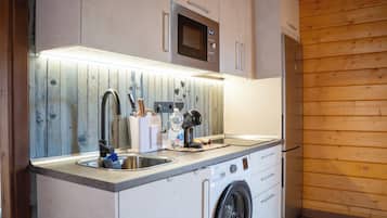 Une cuisine compacte équipée d’un four à micro-ondes encastré, d’un évier et d’un lave-linge.