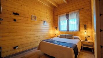 Une chambre dans une cabane en bois, avec un lit, des tables de chevet et une fenêtre avec des rideaux.