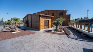 Een modern gebouw met een houten gevel, een verhard pad en een kleine tuin met twee palmboompjes.