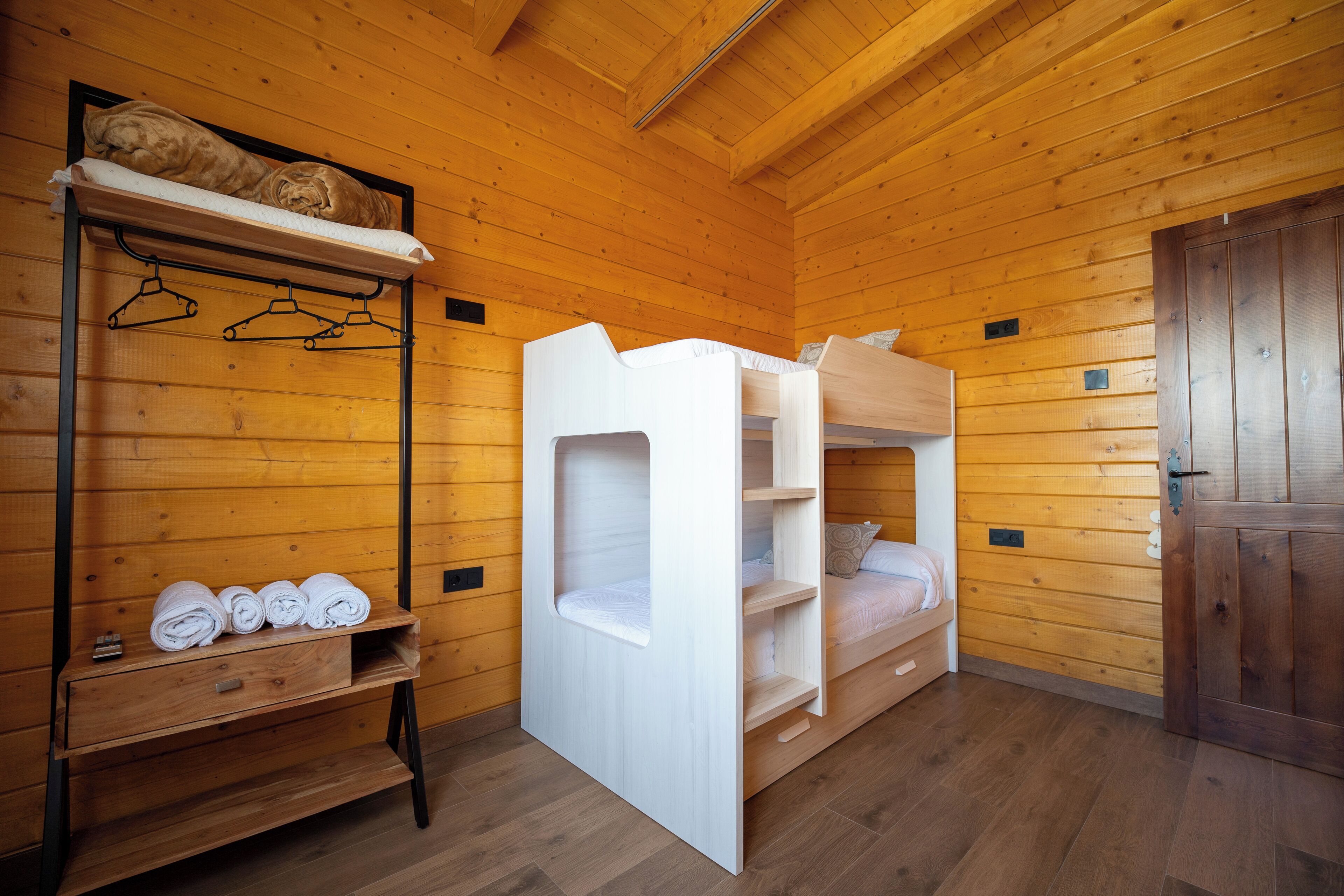 Ein Holzhütten-Zimmer mit Etagenbetten, einem Holzschrank und einem Regal mit Handtüchern.