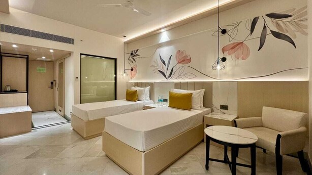 Una camera d'albergo moderna con un letto grande, un divano, un tavolino e una parete decorativa.