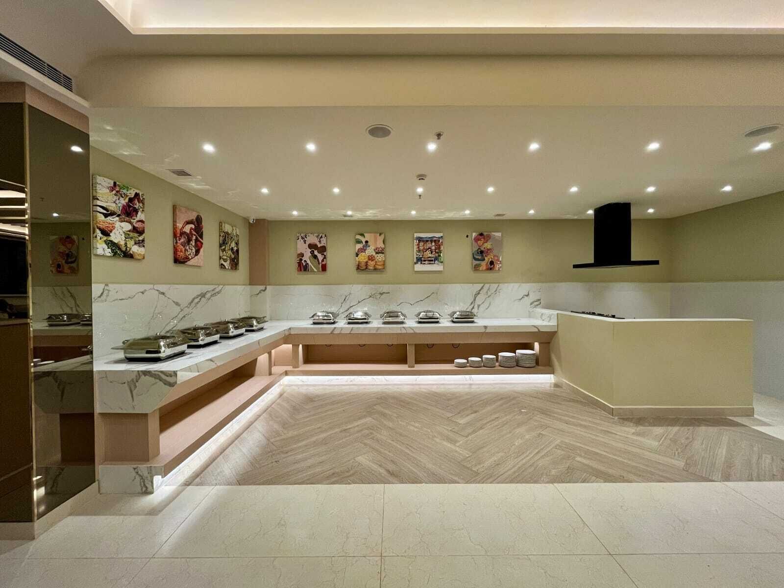 A modern kitchen with marble countertops, a herringbone floor, and artwork on the walls.
