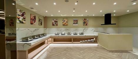 A modern kitchen with marble countertops, a herringbone floor, and artwork on the walls.