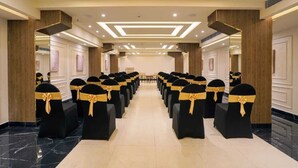 Una sala conferenze d'hotel con file di sedie nere, fasce dorate, un pavimento in marmo e un design moderno del soffitto con illuminazione a incasso.