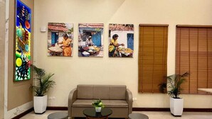 Una hall con un divano, due piante in vaso, un tavolino da caffè e tre quadri appesi al muro.