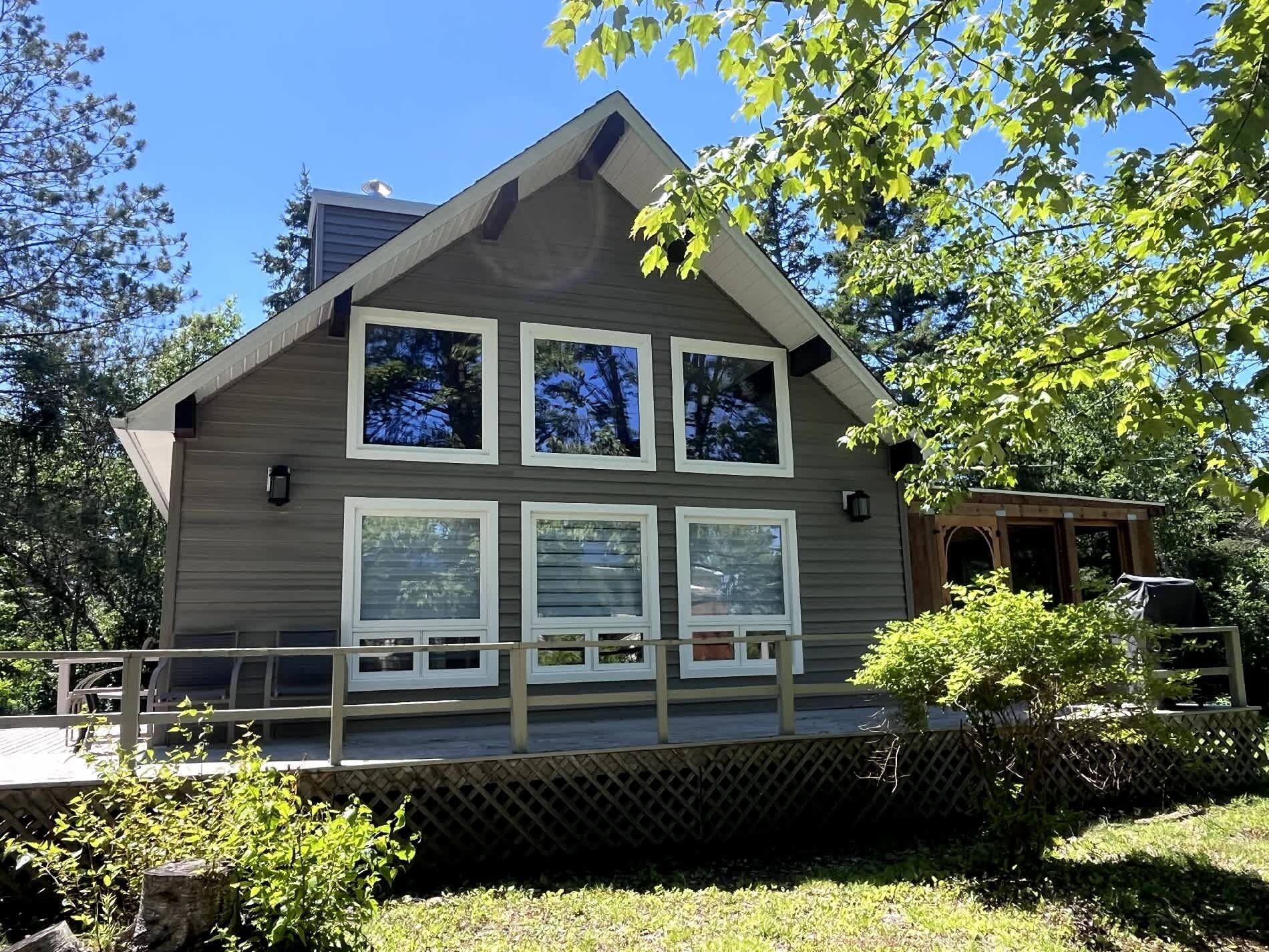 A two-story building with a sloped roof, a wooden deck, and a small porch area.