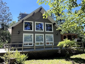 A two-story building with a sloped roof, a wooden deck, and a small porch area.