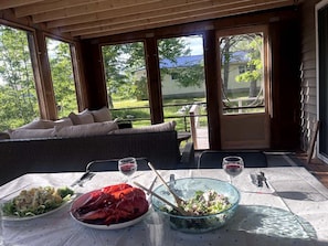 An outdoor dining area with a table set for two, featuring seafood and salad.